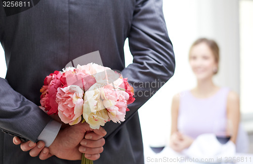 Image of close up of man hiding flowers behind from woman