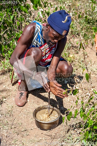 Image of MASAI MARA,KENYA, AFRICA- FEB 12 Masai shaman is preparing a potion in traditional clothes, review of daily life of local people,near to Masai Mara National Park Reserve, Feb 12, 2010,Kenya