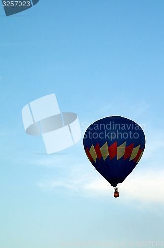 Image of mostly blue hot air balloon flying in sky