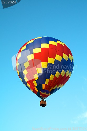 Image of tricolored hot air balloon flying in sky