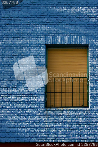 Image of old yellow window in light blue wall 