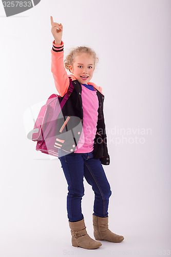 Image of Blond small girl with school bag on the back, points with the finger in the air