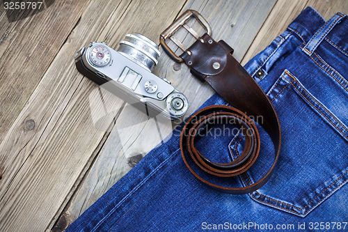 Image of rangefinder camera, vintage leather belt and blue jeans