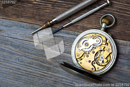 Image of antique clock with an open mechanism and two screwdrivers