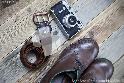 Image of sturdy brown boots, leather belt, and rangefinder camera