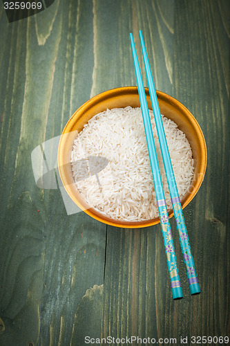 Image of Uncooked rice grains in wood bowl