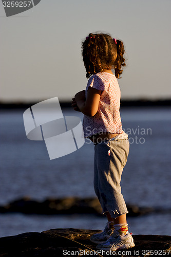 Image of little girl in the sunrise near the  beach