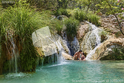 Image of Couple hugging and kissing under waterfall