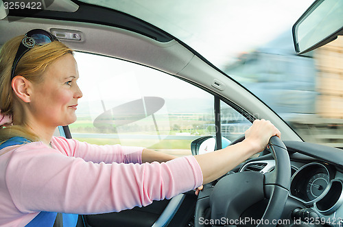Image of Attractive adult woman safe carefully driving car suburban road