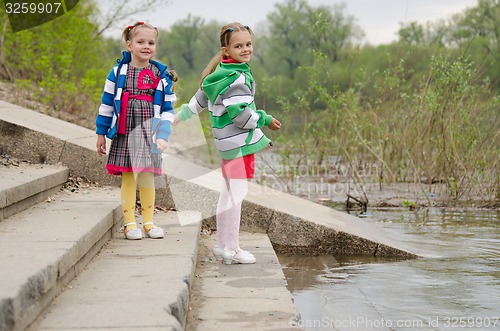 Image of Two girls standing on the steps near water