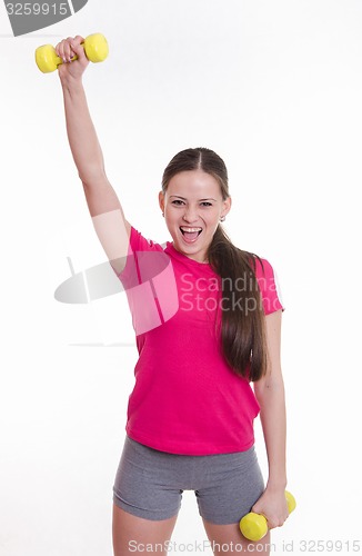 Image of Sportswoman happily raised his right hand with a dumbbell