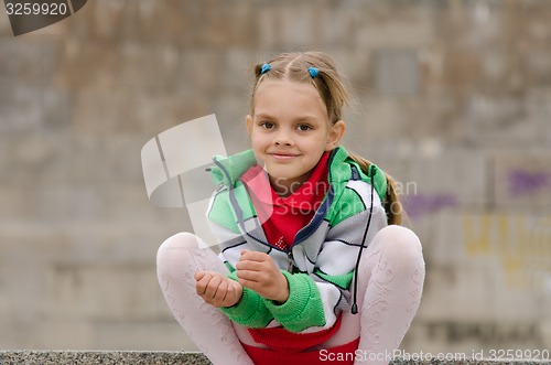 Image of Six year old girl crouched on the background of a granite wall