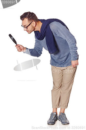 Image of Serious man looking through magnifying glass