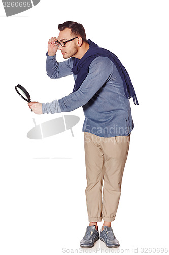 Image of Serious man looking through magnifying glass