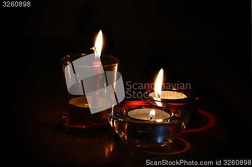 Image of Three burning candles in the dark