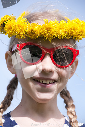Image of smiling girl in sunglasses and dandelion garland