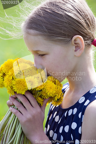 Image of young girl smelling a bunch of dandelions 