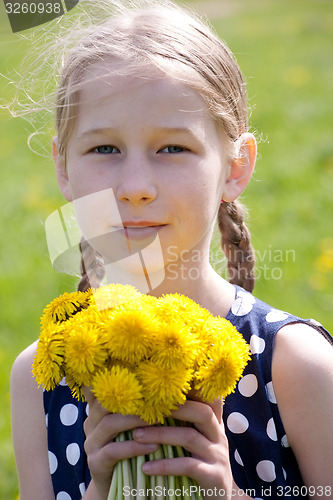 Image of young girl with a bunch of yellow dandelions 