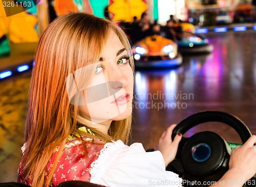 Image of Beautiful girl in an electric bumper car at amusement park