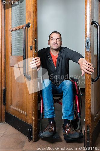 Image of Man in wheelchair stuck between swing doors