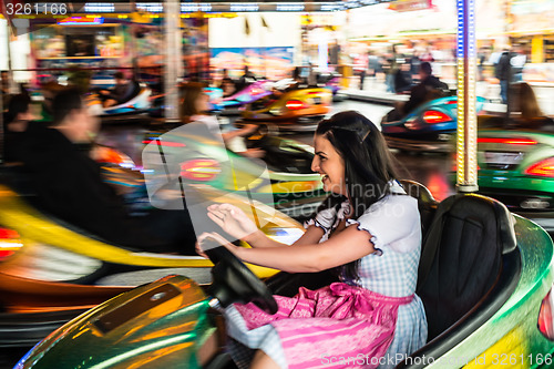 Image of Beautiful girl in an electric bumper car at amusement park