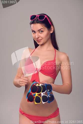 Image of Woman in bikini holding many colourful sunglasses