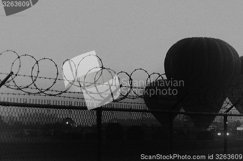 Image of grainy dramatic image of hot air balloons behind barbed wire fence