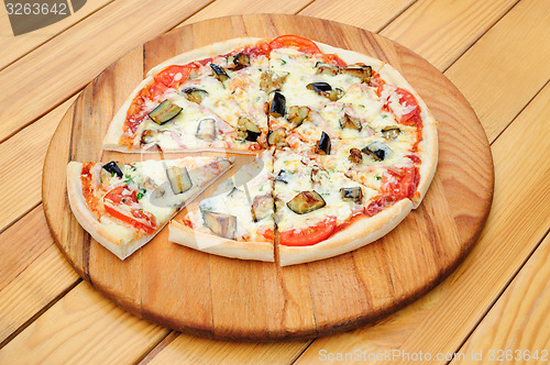 Image of Sliced pizza with ham, aubergine, black olives and corn