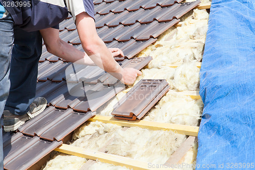 Image of a roofer laying tile on the roof