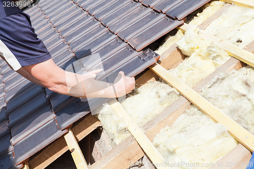 Image of a roofer laying tile on the roof