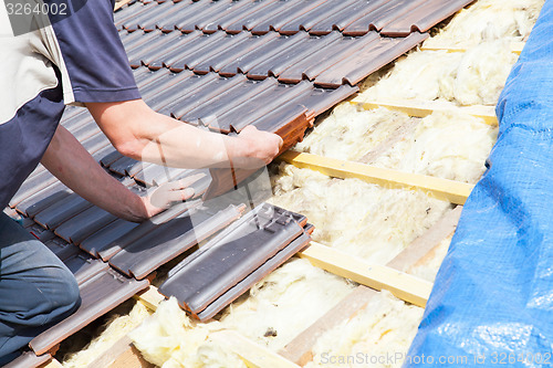 Image of a roofer laying tile on the roof