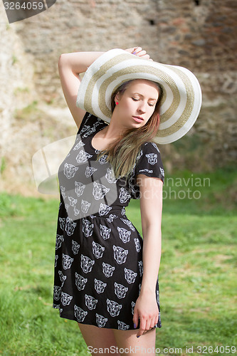Image of Cheerful fashionable woman in stylish hat and frock posing