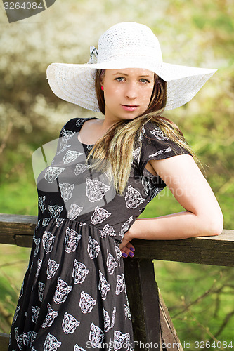 Image of Cheerful fashionable woman in stylish hat and frock posing