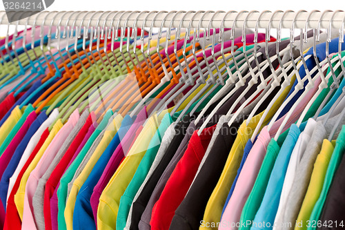 Image of Colored shirts on hangers steel closeup.