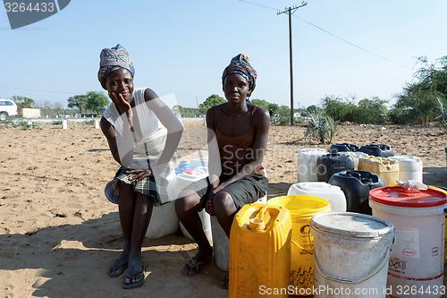 Image of Unidentified Namibian woman with child near public tank with dri