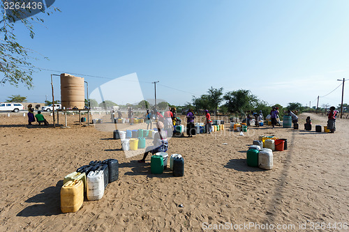 Image of Unidentified Namibian woman with child near public tank with dri