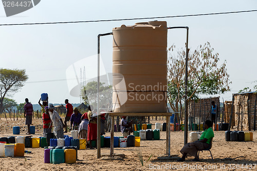 Image of Unidentified Namibian woman with child near public tank with dri