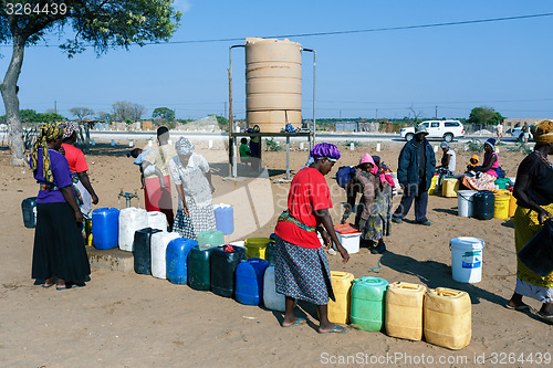 Image of Unidentified Namibian woman with child near public tank with dri