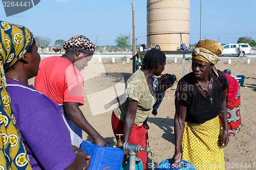 Image of Unidentified Namibian woman with child near public tank with dri