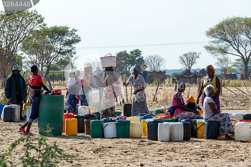 Image of Unidentified Namibian woman with child near public tank with dri