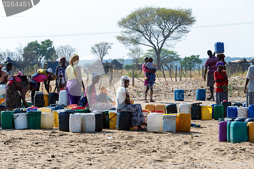 Image of Unidentified Namibian woman with child near public tank with dri