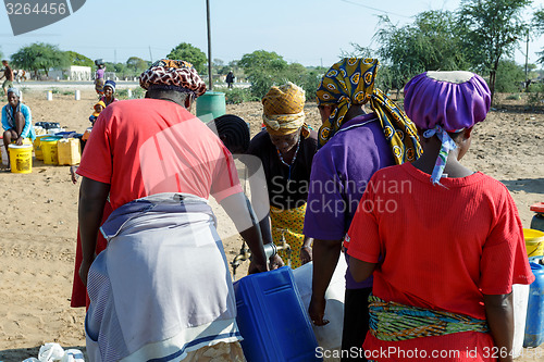 Image of Unidentified Namibian woman with child near public tank with dri