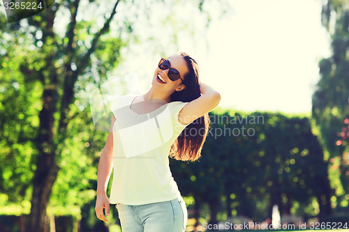 Image of smiling young woman with sunglasses in park