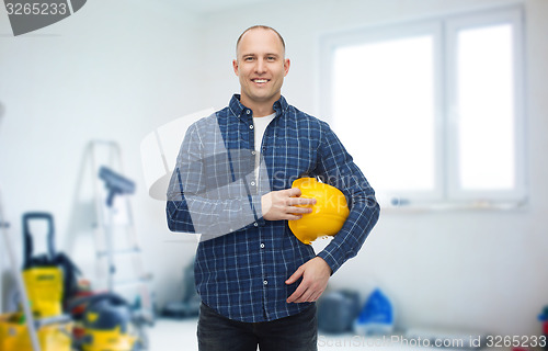 Image of smiling man holding helmet over room background