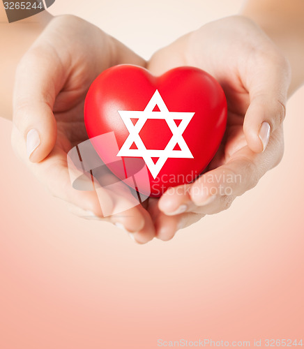 Image of close up of hands holding heart with jewish star