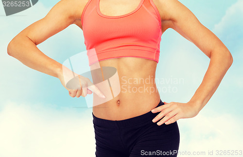 Image of close up of woman pointing finger at her six pack
