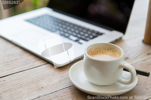 Image of close up of laptop and coffee cup on office table