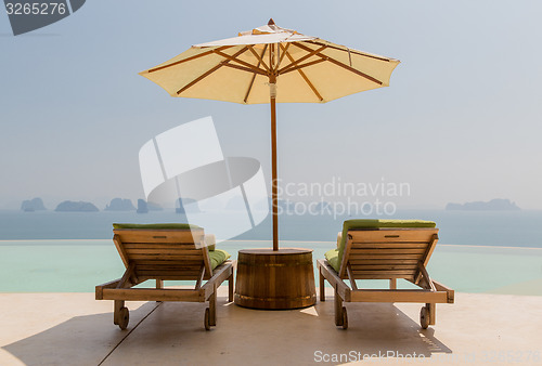 Image of infinity pool with parasol and sun beds at seaside