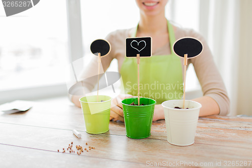 Image of close up of woman over pots with soil and signs