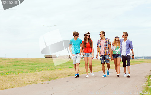 Image of group of smiling teenagers walking outdoors